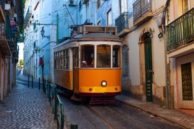 Klasik bir ünlü sarı tramvay Lizbon 'da sabah erken saatlerde canlı kırmızı tarihi binaların önünden geçiyor.