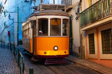 Klasik bir ünlü sarı tramvay Lizbon 'da sabah erken saatlerde canlı kırmızı tarihi binaların önünden geçiyor.