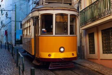 Klasik bir ünlü sarı tramvay Lizbon 'da sabah erken saatlerde canlı kırmızı tarihi binaların önünden geçiyor.