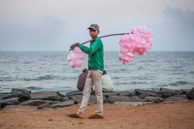 Pondicherry, Hindistan - 20 Ocak 2015. Hindistan 'da popüler şeker satan genç adam deniz kenarında şekerleme satıyor.