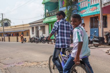 PONDICHERRY, INDIA - 20 Ocak 2015: Genç çocuklar Pondicherry Hint kasabasının geleneksel evlerinin önünden bisikletle geçiyorlar