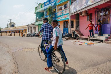 PONDICHERRY, INDIA - 20 Ocak 2015: Genç çocuklar Pondicherry Hint kasabasının geleneksel evlerinin önünden bisikletle geçiyorlar