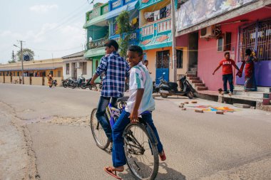PONDICHERRY, INDIA - 20 Ocak 2015: Genç çocuklar Pondicherry Hint kasabasının geleneksel evlerinin önünden bisikletle geçiyorlar