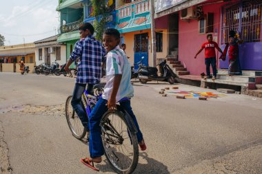PONDICHERRY, INDIA - 20 Ocak 2015: Genç çocuklar Pondicherry Hint kasabasının geleneksel evlerinin önünden bisikletle geçiyorlar