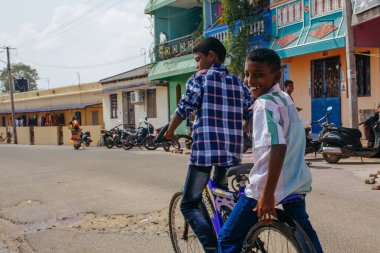 PONDICHERRY, INDIA - 20 Ocak 2015: Genç çocuklar Pondicherry Hint kasabasının geleneksel evlerinin önünden bisikletle geçiyorlar