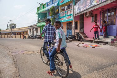 PONDICHERRY, INDIA - 20 Ocak 2015: Genç çocuklar Pondicherry Hint kasabasının geleneksel evlerinin önünden bisikletle geçiyorlar