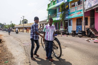 PONDICHERRY, INDIA - 20 Ocak 2015: Genç çocuklar Pondicherry Hint kasabasının geleneksel evlerinin önünden bisikletle geçiyorlar