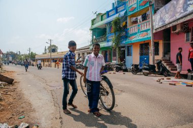 PONDICHERRY, INDIA - 20 Ocak 2015: Genç çocuklar Pondicherry Hint kasabasının geleneksel evlerinin önünden bisikletle geçiyorlar