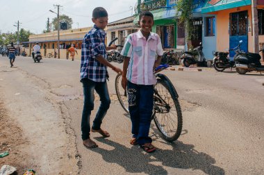 PONDICHERRY, INDIA - 20 Ocak 2015: Genç çocuklar Pondicherry Hint kasabasının geleneksel evlerinin önünden bisikletle geçiyorlar