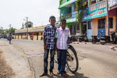 PONDICHERRY, INDIA - 20 Ocak 2015: Genç çocuklar Pondicherry Hint kasabasının geleneksel evlerinin önünden bisikletle geçiyorlar