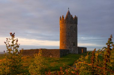 İrlanda Doonegore Şatosu ve Doolin ve Aran Adaları kıyı sahili manzaralı güzel bir gün batımı manzarası..