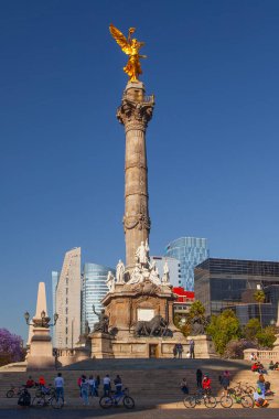 Mexico City, Meksika - 14 Mart 2022: Güneşli bir bahar gününde Özgürlük Anıtı ve döner kavşak, modern binalar ve arka planda çiçek açan Jacaranda ağaçları