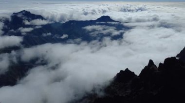 Bulutların üstündeki hava manzarası Caldera de Taburiente Ulusal Parkı 'nın çarpıcı volkanik kaya oluşumlarına bakıyor.