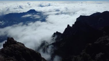 Bulutların üstündeki hava manzarası Caldera de Taburiente Ulusal Parkı 'nın çarpıcı volkanik kaya oluşumlarına bakıyor.