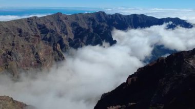 Bulutların üstündeki hava manzarası Caldera de Taburiente Ulusal Parkı 'nın çarpıcı volkanik kaya oluşumlarına bakıyor.