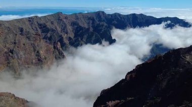 Bulutların üstündeki hava manzarası Caldera de Taburiente Ulusal Parkı 'nın çarpıcı volkanik kaya oluşumlarına bakıyor.