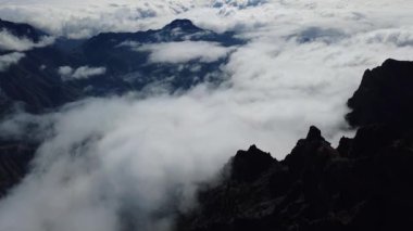Bulutların üstündeki hava manzarası Caldera de Taburiente Ulusal Parkı 'nın çarpıcı volkanik kaya oluşumlarına bakıyor.