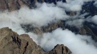 Bulutların üstündeki hava manzarası Caldera de Taburiente Ulusal Parkı 'nın çarpıcı volkanik kaya oluşumlarına bakıyor.