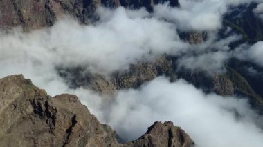 Bulutların üstündeki hava manzarası Caldera de Taburiente Ulusal Parkı 'nın çarpıcı volkanik kaya oluşumlarına bakıyor.
