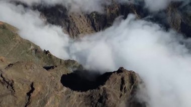 Bulutların üstündeki hava manzarası Caldera de Taburiente Ulusal Parkı 'nın çarpıcı volkanik kaya oluşumlarına bakıyor.