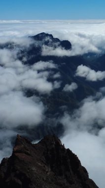 Bulutların üstündeki hava manzarası Caldera de Taburiente Ulusal Parkı 'nın çarpıcı volkanik kaya oluşumlarına bakıyor.