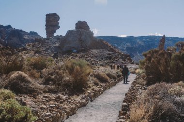 Teide, Tenerife, 13 Ocak 2026: Turistler, Teide Ulusal Parkı 'ndaki heybetli Teide Dağı eteklerinde uzanan toprak ve bazalt kayaları boyunca yürür.