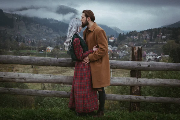 Young happy romantic couple on wooden fence — Stock Photo, Image