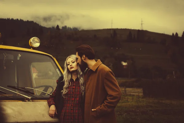 Pareja enamorada cerca de coche amarillo en las montañas Karpathian — Foto de Stock