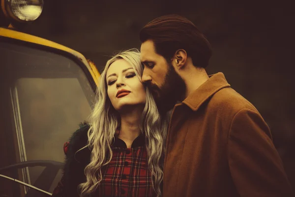 Couple in love near yellow car in Karpathian mountains — Stock Photo, Image