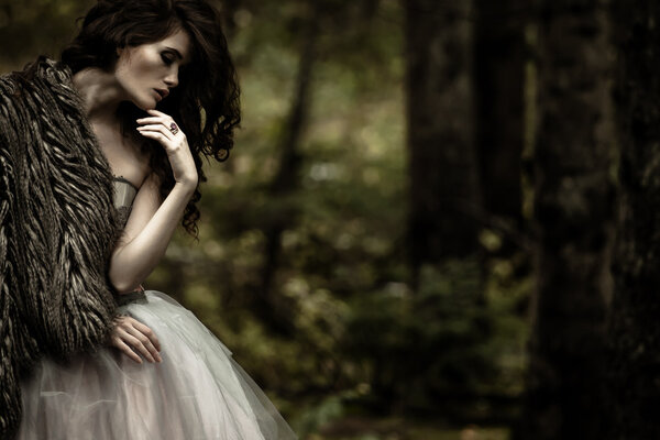 Portrait of romantic woman in beautiful dress in forest