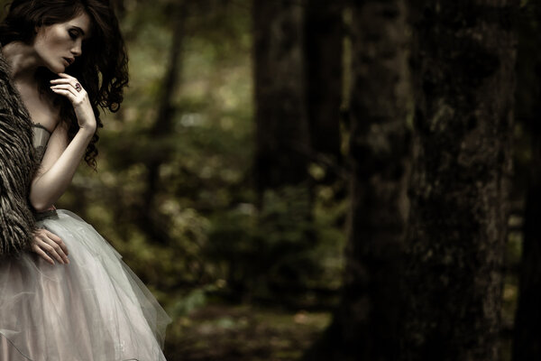 Portrait of romantic woman in beautiful dress in forest