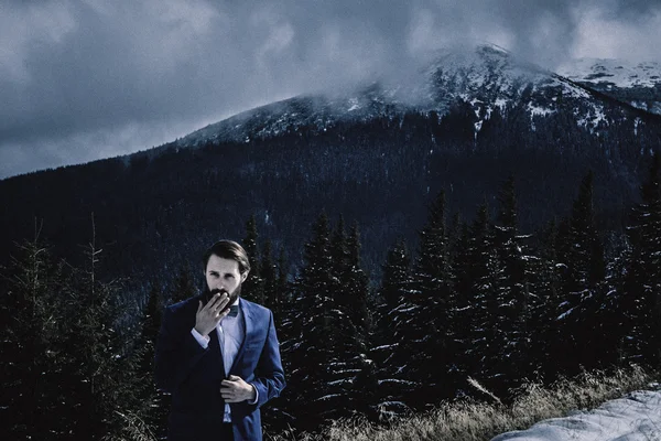 Elegante sposo in montagna nella neve — Foto Stock