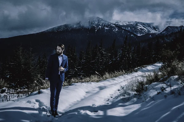 Elegante sposo in montagna nella neve — Foto Stock