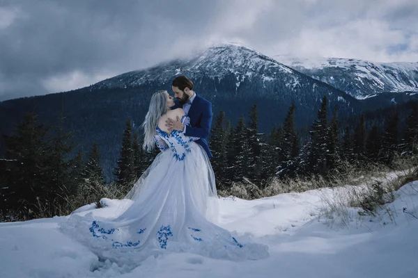 Vackra bruden och brudgummen i vinter snö på berget — Stockfoto