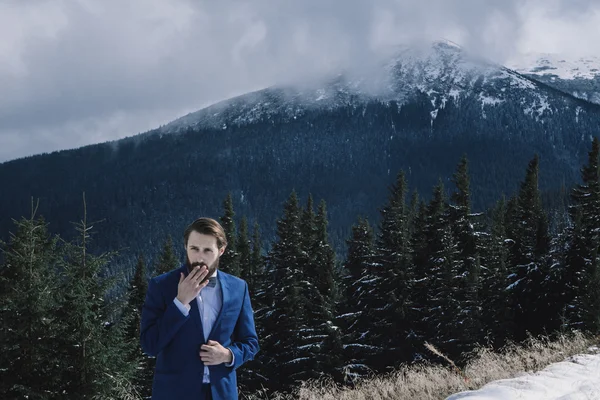 Elegante sposo in montagna nella neve — Foto Stock