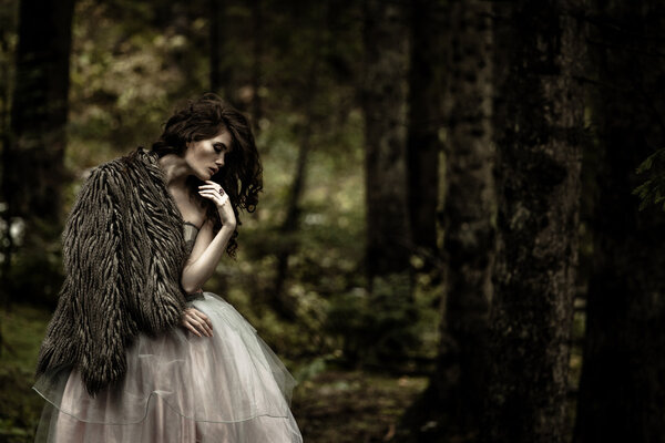 Portrait of romantic woman in beautiful dress in fairy forest