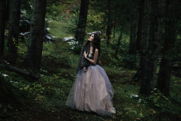 Portrait of romantic woman in beautiful dress in fairy forest