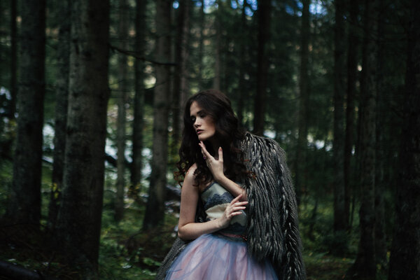 Portrait of romantic woman in beautiful dress in fairy forest