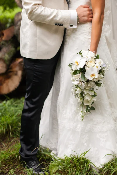 Bräutigam umarmt Braut, die einen Strauß hält — Stockfoto