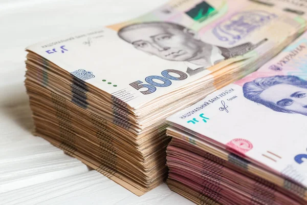 Ukrayna 'nın parası. Beyaz ahşap masanın üzerinde ellerinde bir yığın Ukrayna Hryvnia banknotları. Hryvnia 200 ve 500