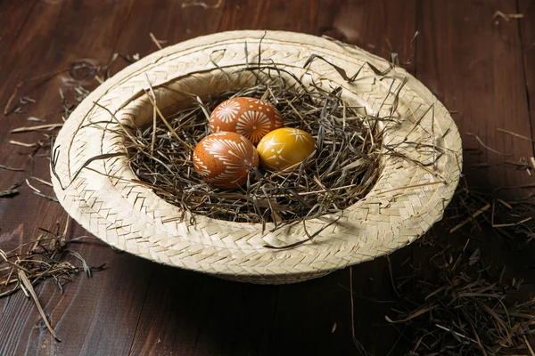 Easter eggs in straw on dark wooden background — Stock Photo, Image