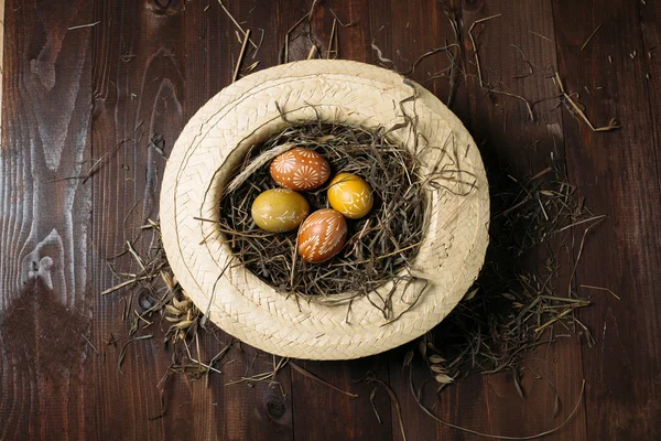 Easter eggs in straw on dark wooden background — Stock Photo, Image