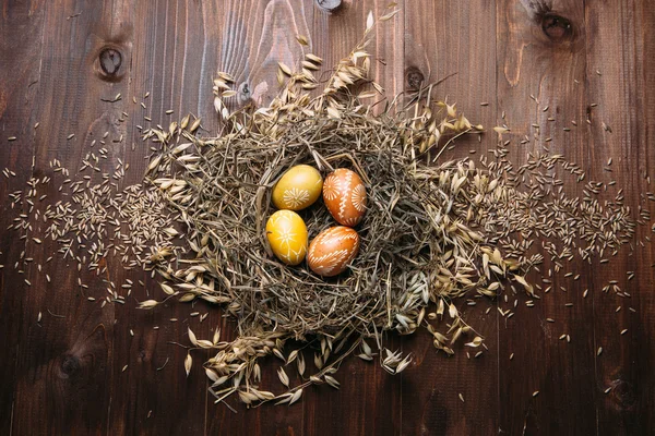 Easter eggs in nest on color wooden background — Stock Photo, Image