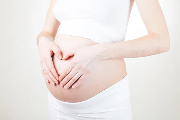 Mulher grávida segurando seus braços da barriga — Fotografia de Stock