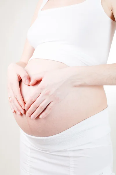 Zwangere vrouw haar buik armen houden — Stockfoto