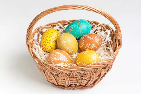 Hand-paited easter eggs in brown basket on white — Stock Photo, Image