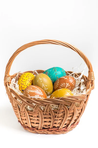 Hand-paited easter eggs in brown basket on white — Stock Photo, Image