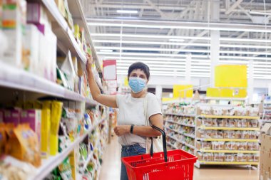 Coronavirüs krizi sırasında ya da covid19 salgını sırasında raftan alışveriş malzemesi almak isteyen bir kız..