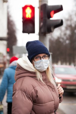 Sokakta kışın giyinmiş ve maske takmış bir kadın. Koronavirüs salgını sırasında koruma teması