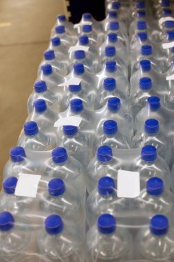 Süpermarkette temiz içme suyu olan mavi kapaklı plastik şişeler. Plastik ambalajla paketlenmiş